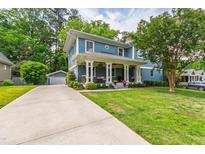 Charming blue two-story home featuring a welcoming front porch, manicured lawn, and ample driveway space at 2517 Medway Dr, Raleigh, NC 27608