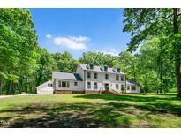 Charming two-story home with landscaped yard surrounded by lush greenery and a long driveway at 318 Hepowil Trce, Hillsborough, NC 27278