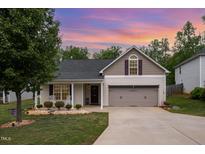 Charming, beige two-story home with a well-manicured lawn and a spacious two-car garage at 334 Huckleberry Loop, Mebane, NC 27302