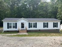 Charming single-story home with white siding, black shutters, and a new roof surrounded by mature trees at 420 Spring Ln, Henderson, NC 27537