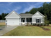 Charming single-story home featuring a two-car garage, stone accents and a well-manicured lawn at 445 Olivia Crossing Ct # 22, Four Oaks, NC 27524