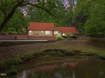 View of exterior of home with pond and surrounding trees and foliage at 4701 Brock Dr, Hurdle Mills, NC 27541