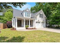 Charming two-story home with white brick, a covered porch, and an attached two-car garage at 715 Kimbrough St, Raleigh, NC 27608