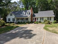 Charming white home featuring a red front door, dormer windows, and well-maintained landscaping at 7401 Walnut Grove Ln, Zebulon, NC 27597
