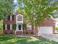 Charming two-story brick home featuring a manicured lawn, symmetrical design, and attached two car garage at 102 Downing Forest Pl, Cary, NC 27519