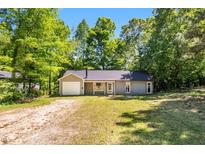 Charming single-story home featuring a one car garage and a gravel driveway, all surrounded by lush trees at 106 Blackfoot Dr, Louisburg, NC 27549