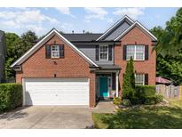 Charming brick home with a two-car garage, teal door, and well-manicured landscaping at 1101 Washhouse Ln, Wake Forest, NC 27587