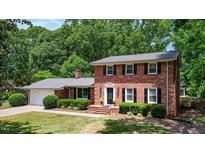 Charming red brick home featuring a well-manicured lawn, mature trees, and classic black shutters at 1274 Candlewood Dr, Elon, NC 27244