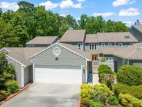 Charming home featuring a pristine white garage door, complemented by lush landscaping and mature trees at 2303 Upper Oaks Way, Raleigh, NC 27615