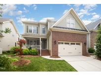 Inviting two-story home featuring brick accents, a well-manicured lawn, and an attached two-car garage at 2728 Cameron Pond Dr, Cary, NC 27519