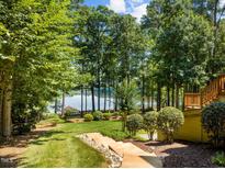 Beautiful backyard lawn with mature trees offers stunning lake views and access from raised deck at 901 Edgewater Dr, Garner, NC 27529
