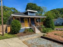 Charming home showcasing a vivid yellow door, complemented by a welcoming wooden porch and appealing blue siding at 1100 Chester St, Durham, NC 27701