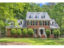 Charming two-story brick home with black shutters, dormer windows, a well-manicured lawn, and mature trees at 11944 Appaloosa E, Raleigh, NC 27613