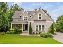 Charming home featuring a landscaped front yard, a covered porch, and a mix of painted brick and gray wood siding at 277 High Ridge Ln, Pittsboro, NC 27312