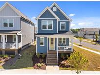 Charming two-story home with blue siding, a welcoming front porch, and a well-manicured lawn in a Gathering-friendly neighborhood at 353 Rivella Dr, Wake Forest, NC 27587