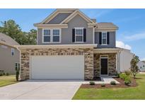Two-story home featuring stone accents, attached garage, and a well-manicured lawn on a sunny day at 364 Peach Grove Way, Lillington, NC 27546