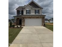 Two-story home with stone accents, a two-car garage, and a well-manicured front lawn at 364 Peach Grove Way, Lillington, NC 27546