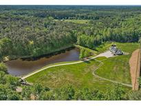 Stunning aerial view of the property featuring a lake, lush greenery, and a beautiful modern home with a swimming pool at 4001 Campbell Rd, Raleigh, NC 27606