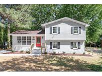 Charming two-story home boasts gray painted brick, white trim, red door, and landscaped yard at 4204 Green Rd, Raleigh, NC 27604