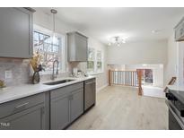 Well-lit kitchen with grey cabinets, stainless steel appliances, white countertops, and an open view to the dining area at 4204 Green Rd, Raleigh, NC 27604