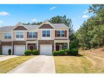 Beautiful townhome featuring a stone facade, red shutters, and a well-manicured lawn and driveway at 513 Commons Dr, Holly Springs, NC 27540