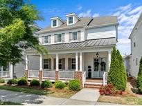 Charming two-story home boasting a welcoming front porch, white siding, dormer windows, and manicured landscaping at 5217 Beckom St, Raleigh, NC 27616