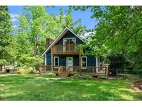 Charming blue house with a spacious wooden porch and balcony, surrounded by lush greenery at 5346 Deep River Rd, Sanford, NC 27330