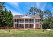 Stately brick home with a double porch and mature trees, offering classic curb appeal and southern charm at 55 Fleming Forest Dr, Youngsville, NC 27596