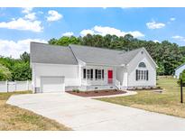 Charming single-story home featuring a red front door, attached garage, and well-maintained landscaping at 5612 Sandy Trail Dr, Knightdale, NC 27545