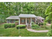 Charming brick home featuring a well-maintained lawn, mature trees, and a welcoming front porch at 5825 Scalybark Rd, Durham, NC 27712