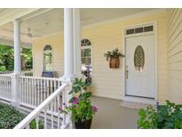 Charming front porch featuring white columns, ample seating, and a decorative front door at 7716 Micklewaithe Ct, Wake Forest, NC 27587