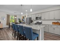 Modern kitchen features a center island with granite countertops and seating, stainless steel appliances and gray cabinets at 820 Laurel Gate Dr, Wake Forest, NC 27587
