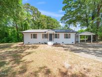 Charming white brick home featuring a metal roof, brown shutters, and a convenient carport at 8731 Raleigh, Benson, NC 27504