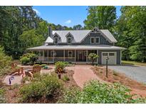 Charming two-story home features a long front porch, brick walkway, and beautifully landscaped front yard at 9625 Collins Creek Dr, Chapel Hill, NC 27516
