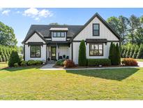 Charming two-story home with black trim, American flag, landscaped yard, and well-manicured lawn at 15 Willow Bend Dr, Youngsville, NC 27596