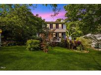 Charming two-story home with red shutters, lovely landscaping, and a lush lawn surrounded by mature trees at 1924 Strebor St, Durham, NC 27705