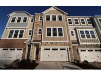 New townhome with attached garage and a mixed material facade of siding and stone under a clear blue sky at 2297 Bay Minette Sta # 536, Apex, NC 27502