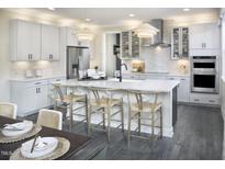 This kitchen features white cabinets, stainless steel appliances, an island with barstool seating, and modern lighting at 3725 Lebrun Path # 151 Lassen Fh, Fuquay Varina, NC 27526