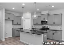 Modern kitchen with gray cabinets, black countertops, stainless steel appliances, and pendant lighting at 3918 Well Fleet Dr, Fuquay Varina, NC 27526