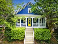 Charming blue craftsman home with a bright yellow front door, covered porch, and landscaped front yard at 420 Marsh Landing Dr, Holly Springs, NC 27540