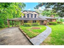 Charming Tudor-style home with lush landscaping, a covered driveway, and a beautiful stone walkway at 502 Hiddenbrook Dr, Durham, NC 27703