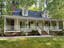 Charming home with a welcoming front porch, lush landscaping, and a brick chimney at 524 Preston Andrews Rd, Bahama, NC 27503