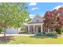 Charming home featuring manicured lawn, lush landscaping, and a welcoming front porch with classic architectural details at 716 Arbor Brook Dr, Cary, NC 27519