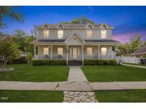 Charming two-story home boasts a welcoming front porch, lush lawn, and manicured landscaping at 104 N Green St, Selma, NC 27576