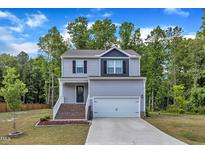 Charming two-story home with gray siding, brick stairs, a two-car garage, and a beautiful tree-lined background at 115 Parkers Gate Dr, Youngsville, NC 27596