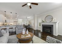 Open living room featuring a fireplace, ceiling fan, and dark hardwood flooring at 1211 Brown Velvet Ln, Apex, NC 27523