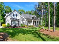 Beautifully landscaped white home with rocking chair front porch at 165 Alpine Rd, Moncure, NC 27559