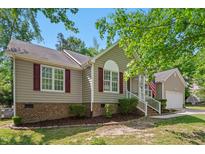Charming single-story home with tan siding, red shutters, an American flag, and an attached garage at 1998 Ferbow St, Creedmoor, NC 27522