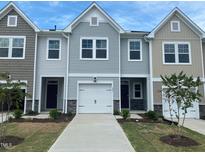 Charming townhome featuring a clean driveway, white garage, and complementary landscape for an inviting curb appeal at 247 Paramount Dr # 104, Smithfield, NC 27577