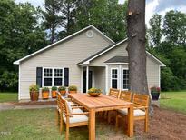 Charming single-story home featuring a cozy outdoor dining area and lush landscaping at 284 Irvan St, Clayton, NC 27520